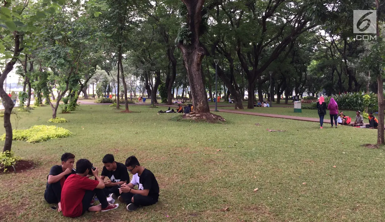 Pengunjung bersantai sambil bercengkerama di sekitar Taman Monas, Jakarta, Rabu (17/1). Dibukanya pagar pembatas Taman Monas membuat warga bisa masuk ke area taman yang mengelilingi lokasi wisata di Ibu Kota tersebut. (Liputan6.com/Immanuel Antonius)
