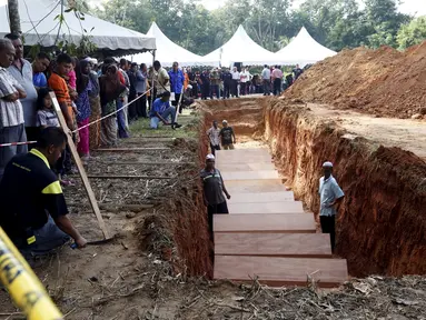 Sejumlah orang menyaksikan pemakaman massal jenazah yang di duga etnis Rohingya di Alor Setar, Malaysia, Senin (22/6/2015).  21 dari 106 jenazah tak dikenal yang ditemukan bulan lalu dimakamkan hari ini. (Reuters/Olivia Harris)