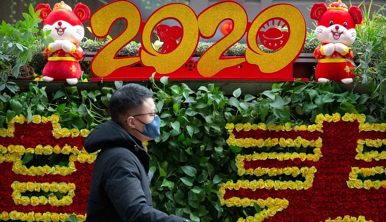 Seorang pria yang mengenakan masker melewati layar perayaan Imlek Tahun Tikus Logam di Stasiun Kereta Api Barat Beijing, 21 Januari 2020. Pihak berwenang China mengonfirmasi telah ada empat orang yang meninggal akibat terinfeksi virus corona jenis baru di pusat kota Wuhan. (AP/Mark Schiefelbein)