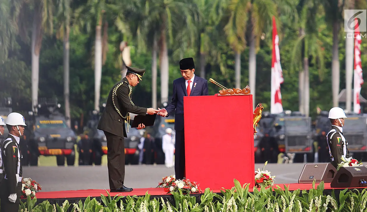 Presiden Jokowi menerima kertas sebelum menyampaikan pidato pada peringatan HUT ke-71 Bhayangkara di Monas, Jakarta, Senin (10/7). Sebanyak 2.408 personel gabungan Polri, TNI, Satpol PP dan Pramuka terlibat dalam upacara ini. (Liputan6.com/Angga Yuniar)