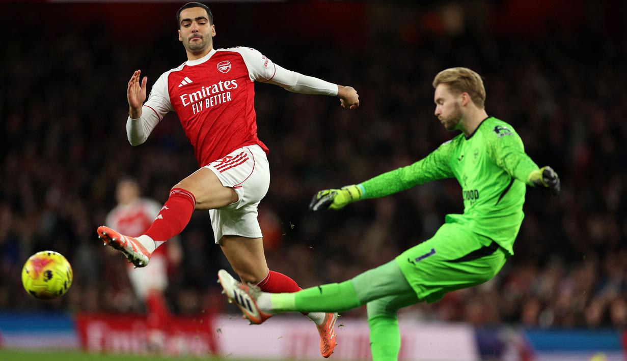 Pemain Arsenal, Mikel Merino (kiri) berusaha merebut bola dari kiper Brentford, Caoimhin Kelleher dalam laga lanjutan Liga Inggris 2025/2026 di Emirates Stadium, London, Inggris, Rabu (03/12/2025) waktu setempat. (AFP/Adrian Dennis)