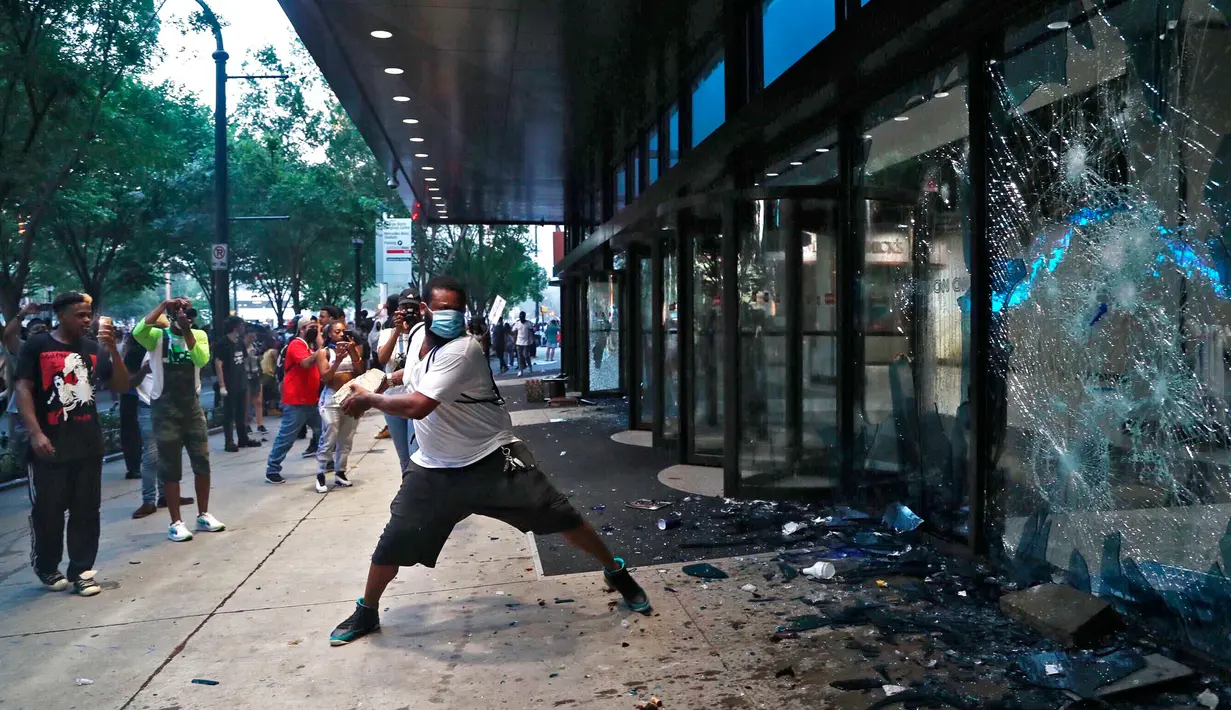 Pengunjuk rasa menghancurkan jendela di kantor pusat CNN di Atlanta, Georgia, Jumat (29/5/2020). Massa yang mengecam kematian George Floyd (46) oleh polisi melakukan vandalisme dan perusakan gedung CNN pusat. (Alyssa Pointer/Atlanta Journal-Constitution via AP)