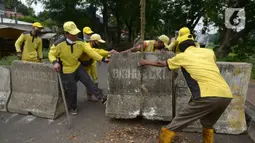 Petugas gabungan memindahkan beton pembatas di Jalur Inspeksi Kanal Banjir Timur (KBT), Cipinang, Jakarta Timur, Kamis (30/12/2021). Kawasan KBT ditutup guna mencegah kerumunan warga yang hendak merayakan malam pergantian tahun. (merdeka.com/Imam Buhori)