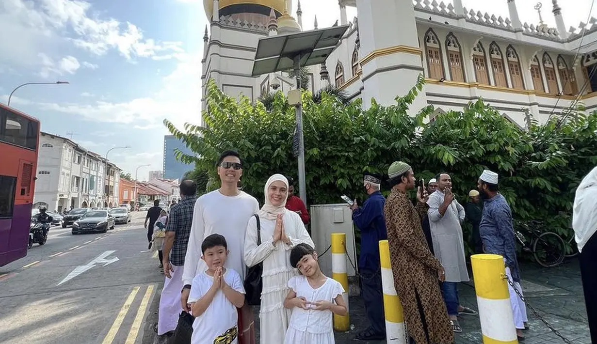 Mengenakan dress lengan panjang putih, Nycta Gina bersama suami dan keduanya merayakan Idul Adha di Singapura.  (@missnyctagina)