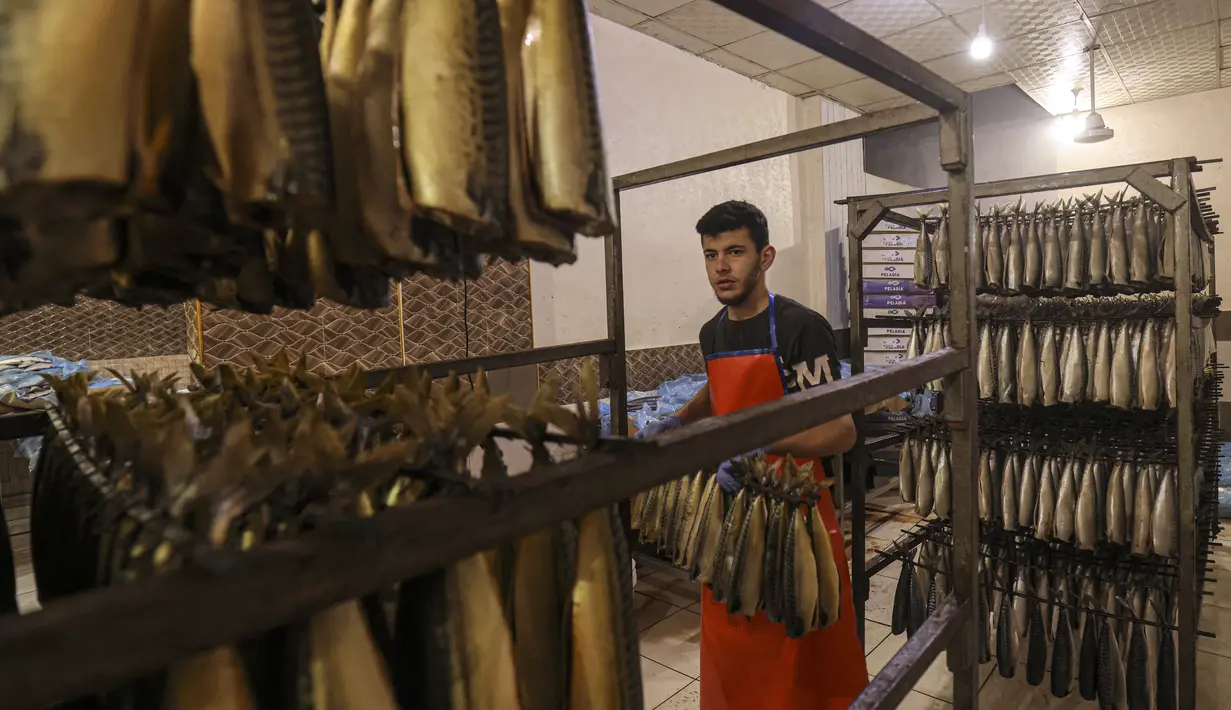 <p>Seorang pemuda Palestina bekerja di fasilitas pengasapan makarel saat ikan itu akan dijual jelang liburan Idul Fitri di Rafah di Jalur Gaza selatan (26/4/2022). Ikan asap makarel menjadi salah satu menu hidangan buka puasa dan Idul Fitri terfavorit bagi warga Gaza selama Ramadhan.(AFP/Said Khatib)</p>