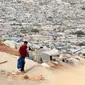 Seorang pemuda kembali dari sekolah ke kamp pengungsian yang penuh sesak selama krisis pandemi virus corona COVID-19 dekat Desa Qah, dekat perbatasan Turki, Idlib, Suriah, 28 Oktober 2020. (Photo by Ahmad al-ATRASH/AFP)