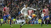 Bintang Real Madrid, Cristiano Ronaldo, mengecoh sejumlah pemain Sporting Gijon. Meski menang, Madrid masih tertahan di posisi tiga klasemen Liga Spanyol. (AFP/Pedro Armestre)