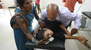 Seorang ayah mencoba menenangkan putrinya yang menderita penyakit terkait panas saat dia dibawa ke rumah sakit distrik pemerintah di Ballia, negara bagian Uttar Pradesh, India, Senin (19/6/2023). (AP Photo/Rajesh Kumar Singh)