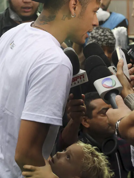Pemain Barcelona, Neymar memeluk anaknya, Davi Lucca saat berbicara di hadapan media pada acara "World Boots" di Neymar Institute, Brasil, 7 Juni 2015.(REUTERS/Paulo Whitaker)