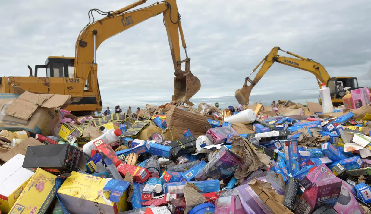 Pekerja dibantu alat berat memusnahkan 60 ton kosmetik palsu di Phnom Penh, Kamboja (3/10). Pada bulan Mei, pihak berwenang Kamboja menyita 68 ton produk kosmetik palsu yang dibuat di negara-negara seperti Jepang dan Korsel. (AFP Photo/Tang Chhin Sothy)