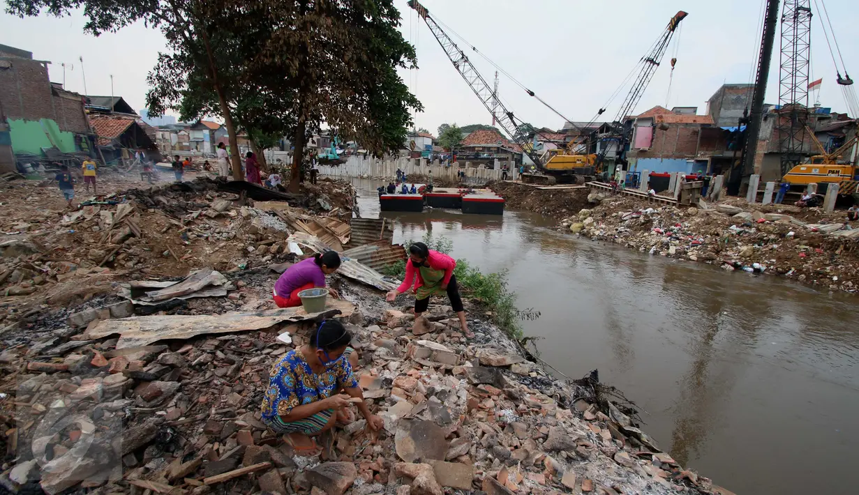 Warga korban gusuran memunguti puing bangunan yang dapat dijual kembali di bantaran Sungai Ciliwung, Bukit Duri, Jakarta, Selasa (20/1). (Liputan6.com/Gempur M Surya)