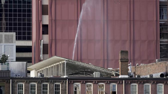 Jendela-jendela pecah dan pipa air yang rusak menyemprot di sebuah gedung dekat lokasi ledakan di pusat kota Nashville, Tennessee, Amerika Serikat, Jumat (25/12/2020). Tim khusus telah diterjunkan untuk melakukan investigasi di lokasi ledakan. (AP Photo/Mark Humphrey)