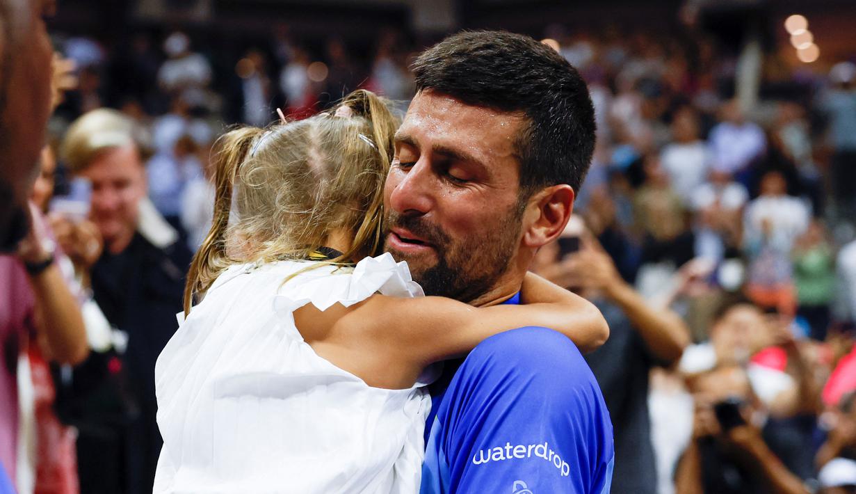 Petenis asal Serbia, Novak Djokovic (kanan), memeluk putrinya, Tara, setelah mengalahkan petenis asal Rusia Daniil Medvedev dalam partai final US Open 2023 yang berlangsung di Arthur Ashe, New York, Senin (11/9/2023) pagi WIB. (AFP/Kena Betancur)