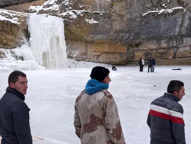 Sejumlah pengunjung melihat air terjun Mirusha yang membeku di Lapceve, Kosovo (9/1). Cuaca bersuhu mencapai minus 20 derajat celcius membuat Air Terjun Mirusha dan kolam membeku. (AFP Photo/Armend Nimani)