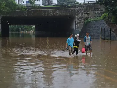 Warga berjalan kaki melintasi kawasan DI Panjaitan, Jakarta, Selasa (25/2/2020). Hujan yang mengguyur Jakarta sejak dini hari tadi membuat kawasan tersebut terendam banjir sehingga tak bisa dilintasi kendaraan bermotor. (Liputan6.com/Herman Zakharia)