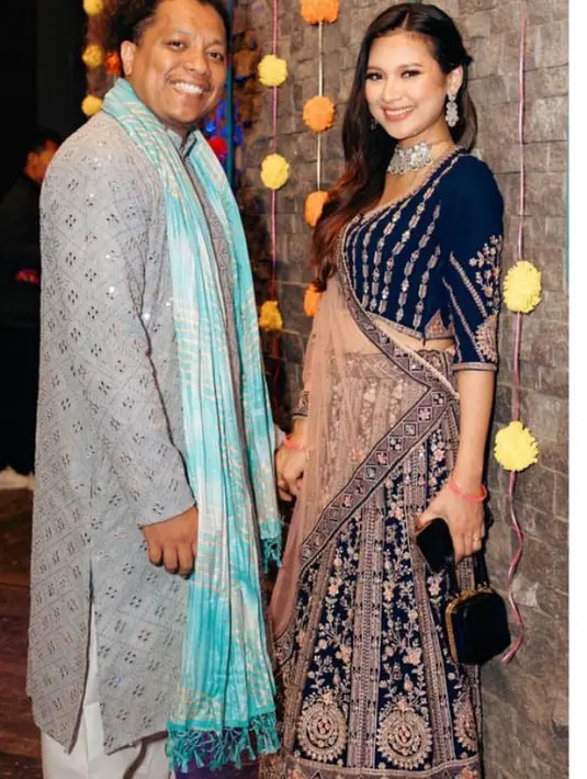 Indah Permatasari hadir mengenakan busana ala perempuan Indonesia lengkap dengan kain sarinya. Sang suami, Arie Kriting mengenakan atasan panjang abu-abu lengkap dengan syal birunya. [@indahpermatasari]