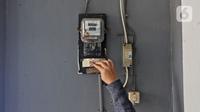 Warga memeriksa meteran listrik di kawasan Matraman, Jakarta, Kamis (2/4/2020). Di tengah pandemi COVID-19, pemerintah menggratiskan biaya tarif listrik bagi konsumen 450 Volt Ampere (VA) dan pemberian keringanan tagihan 50 persen kepada konsumen bersubsidi 900 VA. (Liputan6.com/Herman Zakharia)