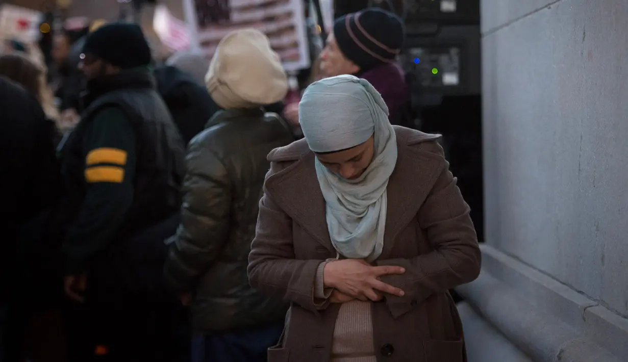 Afaf Nasher telihat khusyuk saat menjalankan salat dikerumunan pendemo lainnya sebelum melakukan aksi protes terhadap Presiden AS Donald Trump di Washington Square Park di New York, AS (25/1). (AFP/Bryan R. Smith)