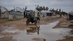 Sejak Desember 2025 hingga awal Januari 2026, dilaporkan sedikitnya 25 warga meninggal dunia terdampak cuaca ekstrem, termasuk anak-anak yang meninggal akibat hipotermia di kamp pengungsian. Tampak dalam foto, seorang anak berjalan di dalam kamp tenda untuk pengungsi Palestina setelah hujan deras di Nuseirat, Jalur Gaza tengah, Jumat, 2 Januari 2026. (AP Photo/Abdel Kareem Hana)