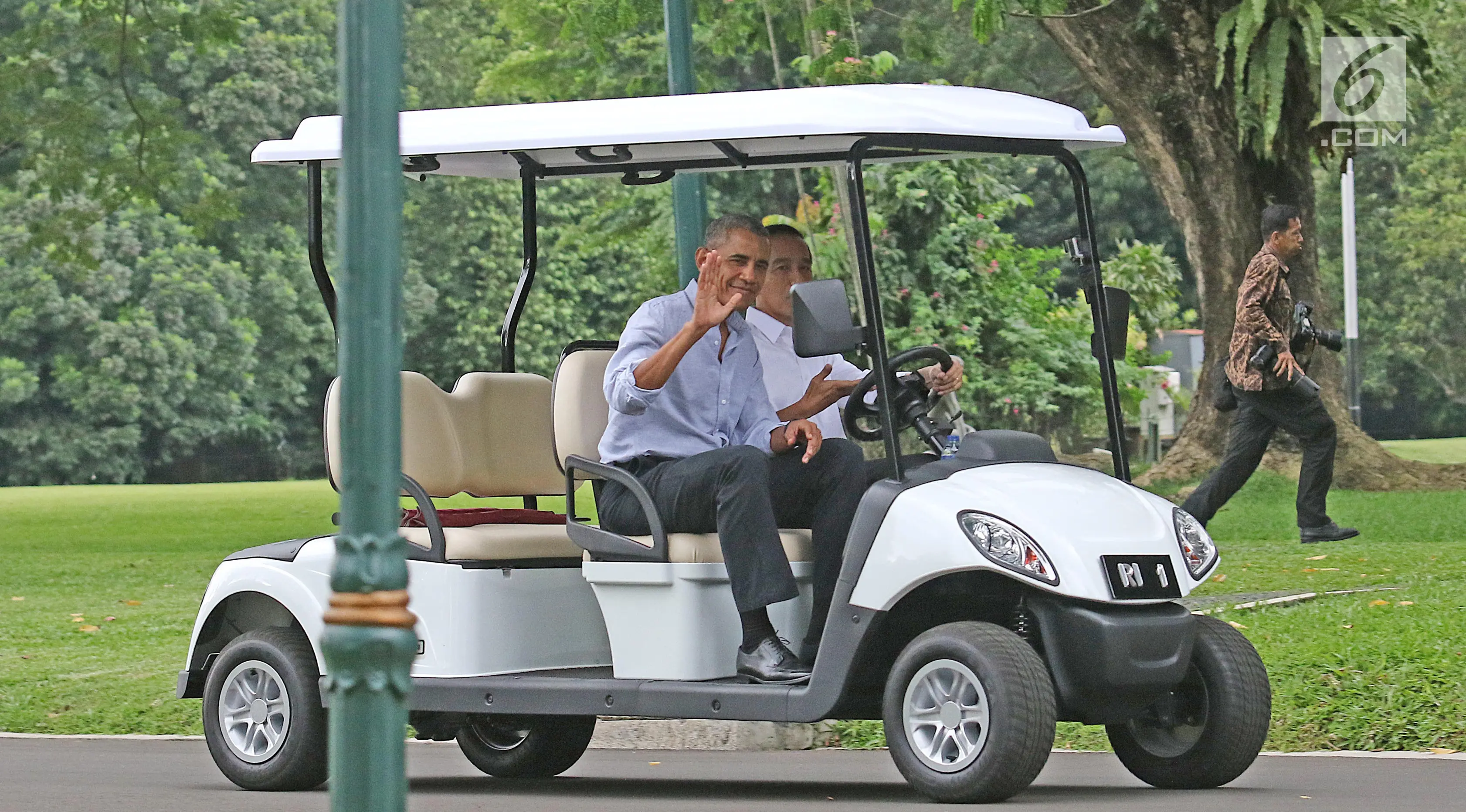 Presiden AS ke-44, Barack Obama ditemani Presiden Jokowi melambaikan tangan saat menaiki mobil golf di Istana Bogor, Jumat (30/6). Jokowi mengendarai golf car untuk mengajak Obama berkeliling Istana dan Kebun Raya Bogor.  (Liputan6.com/Angga Yuniar)