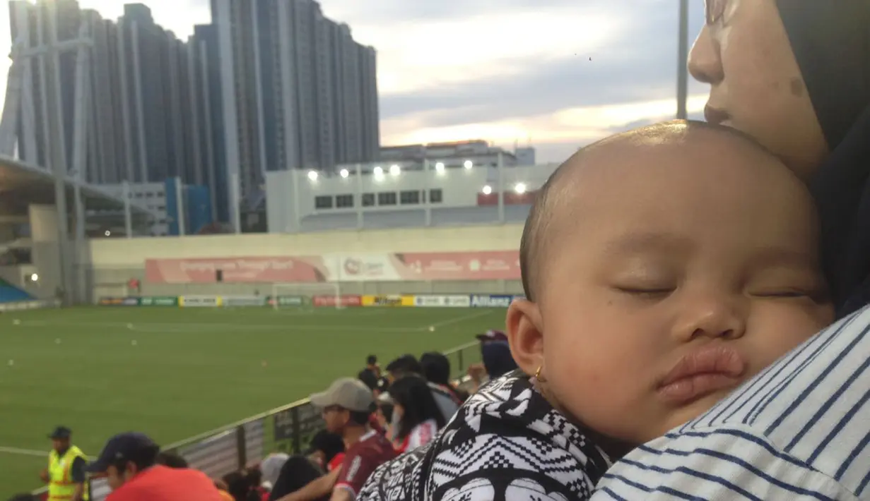 Lelah memberi dukungan untuk Persija Jakarta, pada penghujung laga Rinjani tampak lelah hingga akhirnya terlelap ketika digendong sang ibu. (Bola.com/Mustopha)