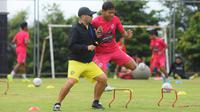Pelatih Arema FC, Javier Roca, saat duel dengan Adam Alis dalam latihan untuk meningkatkan fisik pemainnya, Kamis (22/9/2022). (Bola.com/Iwan Setiawan)