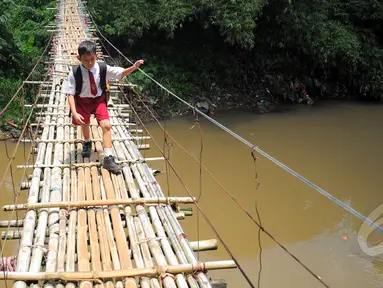 Seorang siswa SD melintas di atas jembatan gantung di atas kali Ciliwung untuk menuju ke sekolah, Jakarta, Selasa (17/3/2015). Jembatan tersebut menghubungkan Kelapa Dua Depok dengan Lenteng Agung (Liputan6.com/Yoppy Renato)
