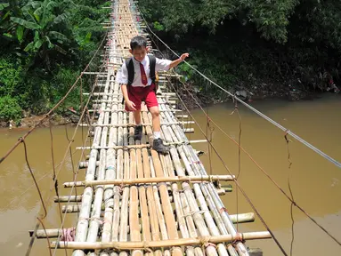 Seorang siswa SD melintas di atas jembatan gantung di atas kali Ciliwung untuk menuju ke sekolah, Jakarta, Selasa (17/3/2015). Jembatan tersebut menghubungkan Kelapa Dua Depok dengan Lenteng Agung (Liputan6.com/Yoppy Renato)