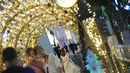 Orang-orang berpose untuk difoto dengan dekorasi lampu Natal di tengah hujan rintik di sepanjang pusat perbelanjaan Orchard Road di Singapura (16/12/2020). Sepanjang jalan di Orchard Road, dihiasi lampu hias, dedaunan artifisial khas natal dan dekorasi lainnya. (Xinhua/Then Chih Wey)