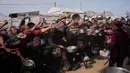 Banyak warga, termasuk anak-anak, berkumpul dengan membawa panci kosong demi mendapatkan satu porsi makanan yang disalurkan di sebuah dapur umum, Khan Younis, Jalur Gaza selatan. Tampak dalam foto, warga Palestina berebut menerima makanan sumbangan di dapur umum, Khan Younis, Jalur Gaza selatan, Jumat 6 Februari 2026. (AP Photo/Abdel Kareem Hana)
