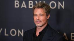 Aktor Brad Pitt berpose untuk fotografer setibanya pada acara premiere film Babylon di Paris, Prancis, 14 Januari 2023. Aktor berusia 59 tahun itu tampak tampan dalam balutan setelan serba hitam. (AP Photo/Michel Euler)