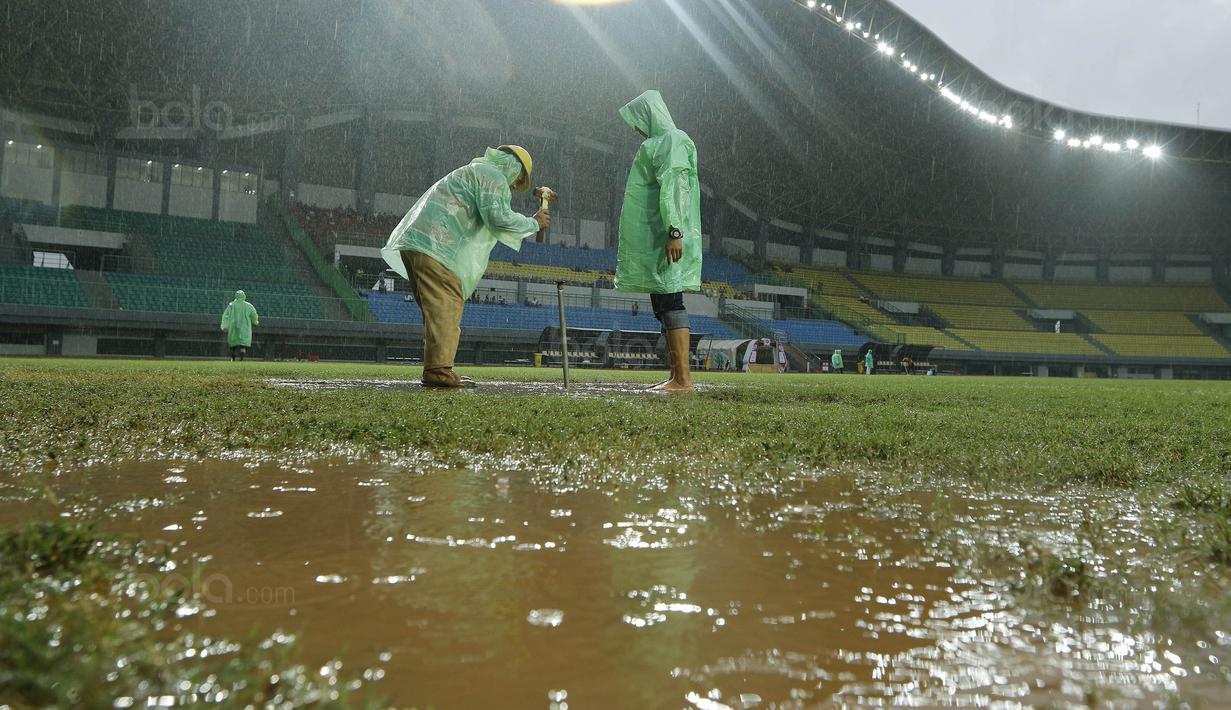 Petugas membuat lubang resapan untuk menguras air yang menggenangi lapangan di Stadion Patriot, Bekasi, Senin (13/11/2017). Drainase yang buruk menyebabkan lapangan terendam air. (Bola.com/M Iqbal Ichsan)