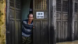 Seorang pria berdiri di tengah banjir di pintu masuk sebuah toko setelah hujan deras di Hoi An, Vietnam, Kamis 30 Oktober 2025. Laporan pemerintah setempat, pada Rabu (29/10/2025), enam dari korban tewas berasal dari Da Nang dan Hoi An, dua kawasan wisata populer di negara itu. (NHAC NGUYEN/AFP)