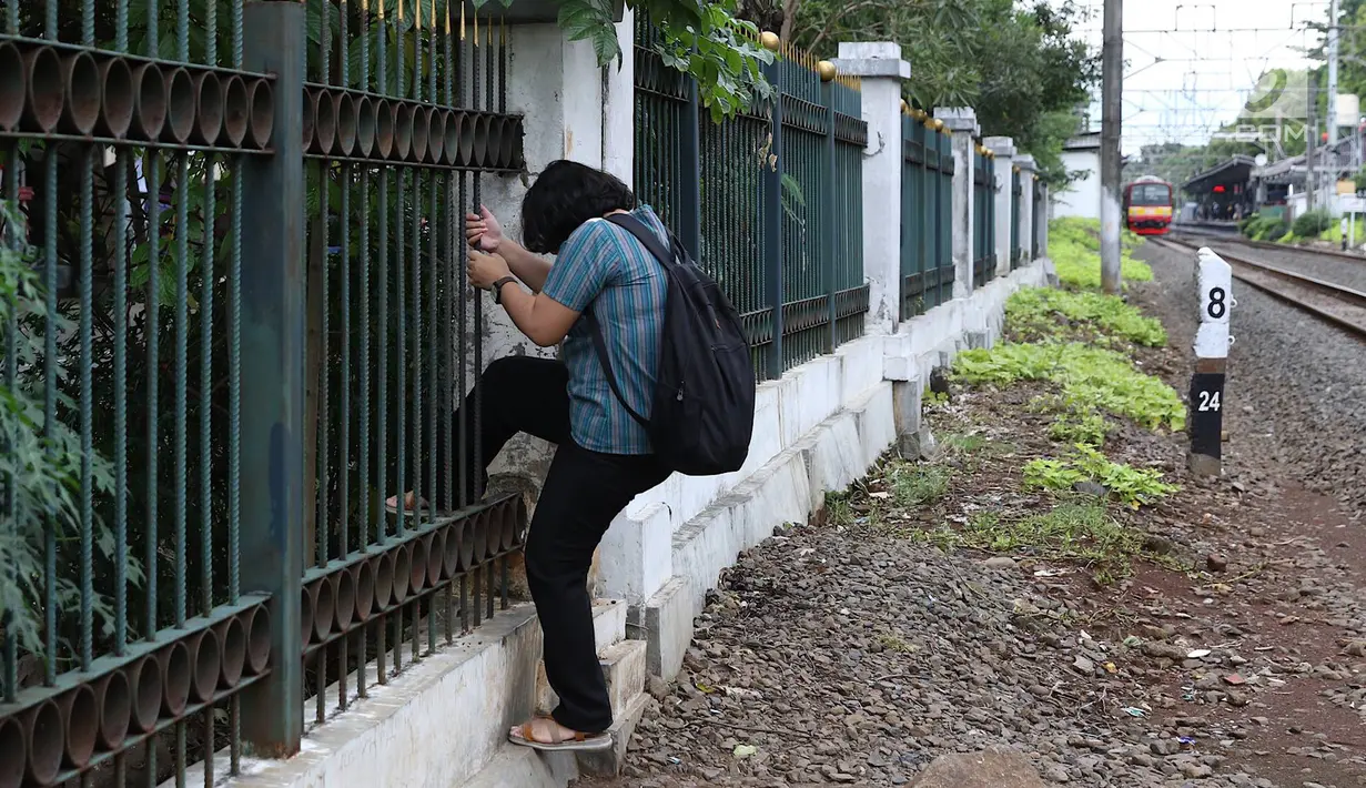 Warga menerobos pagar usai menyeberangi rel kereta api di kawasan Lenteng Agung, Jakarta, Selasa (19/3). Tidak adanya JPO menyebabkan warga harus menerobos pagar besi, meskipun perilaku tersebut berbahaya bagi keselamatan. (Liputan6.com/Immanuel Antonius)