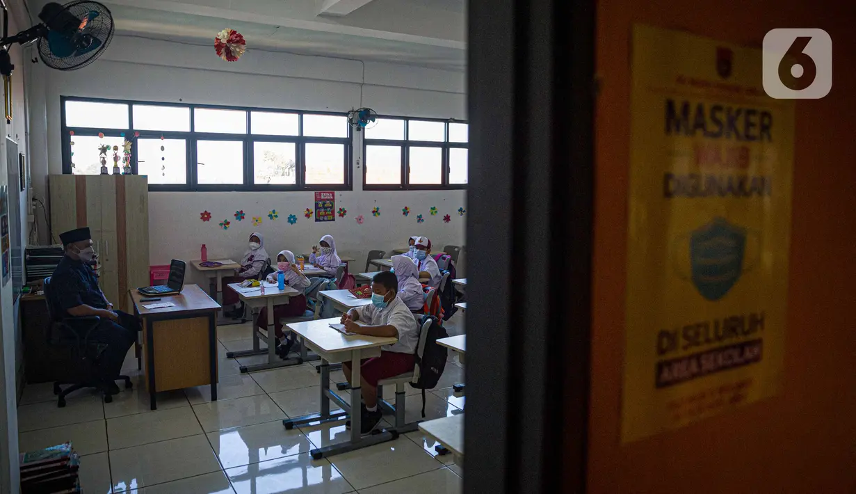 Guru memberi materi kepada siswa saat pembelajaran tatap muka (PTM) di SDN 01 Pondok Labu, Jakarta, Senin (3/1/2022). Pemprov DKI Jakarta menggelar pembelajaran tatap muka (PTM) setiap hari dengan jumlah siswa setiap kelas mencapai 100 persen dari kapasitas. (Liputan6.com/Faizal Fanani)