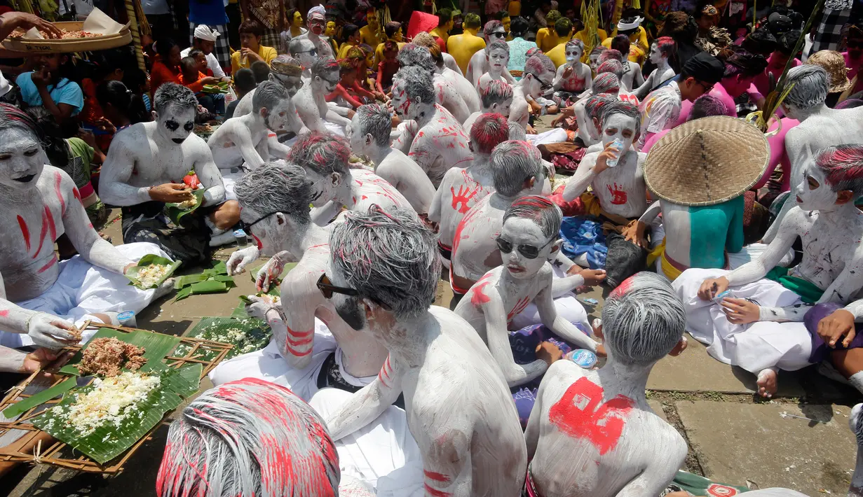 Para pemuda berkumpul di sebuah pura selama ritual Hindu yang disebut "Grebeg" di Desa Tegallalang, Bali, Rabu (30/1). Tradisi ritual berkeliling kampung dengan riasan tubuh warna-warni itu dipercaya sebagai penangkal Roh jahat. (AP/Firdia Lisnawati)