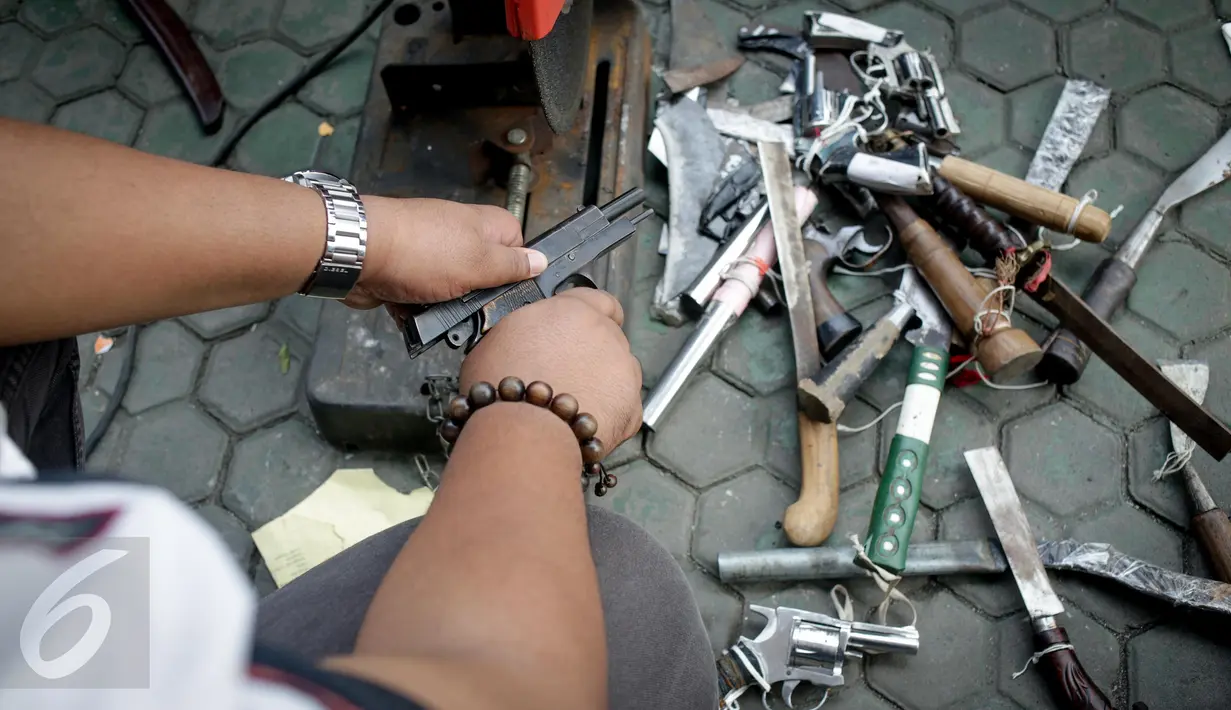 Petugas mengecek senjata api sebelum pemusnahan barang bukti persidangan di Kejaksaan Negeri Jakarta Utara, Kamis (16/3). Delapan unit senjata api rakitan, 57 unit senjata tajam, dan ribuan narkotika ikut dimusnahkan. (Liputan6.com/Faizal Fanani)
