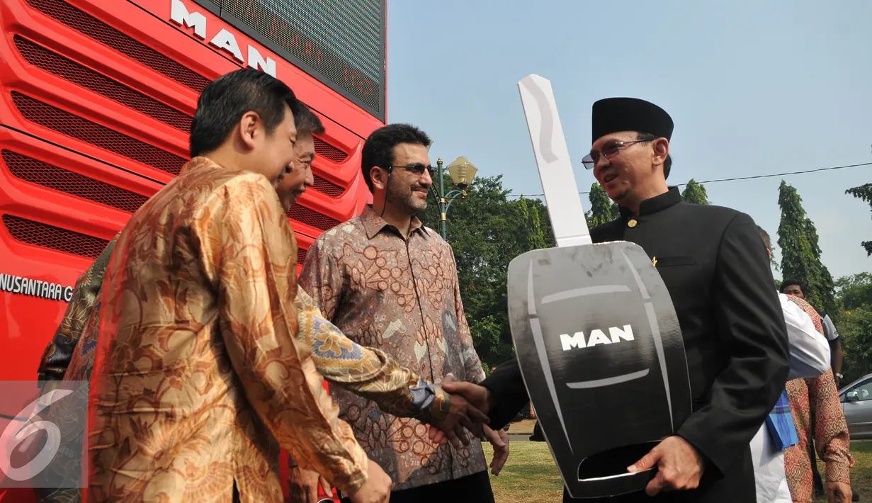 Basuki T Purnama (kanan) menerima kunci bus simbolis saat peluncuran bus-bus baru dan hotline Transjakarta di monas, Jakarta, Senin (22/6/2015). Sebanyak 20 unit bus gandeng Transjakarta buatan eropa resmi diluncurkan. (Liputan6.com/Herman Zakharia)