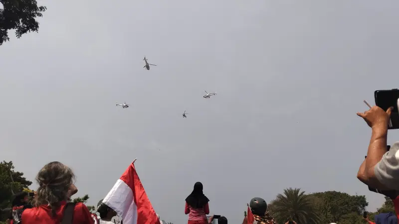 Warga di luar Istana Merdeka menyaksikan atraksi pesawat dan helikopter TNI-Polri dalam peringatan HUT ke-78 RI. (Liputan6.com/ Winda Nelfira)