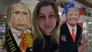 Seorang penjaga toko menunjukan Matryoshka yang berkarakter Presiden Rusia, Vladimir Putin dan Presiden Amerika Serikat terpilih Donald Trump di Moskow, Rusia (16/1). (AFP/Alexander Nemenov)