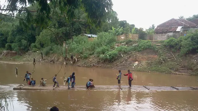 Nampak warga dan pelajar di dua desa di Garut, menggunakan akses rakit bambu untuk melintasi sungai Cimanuk