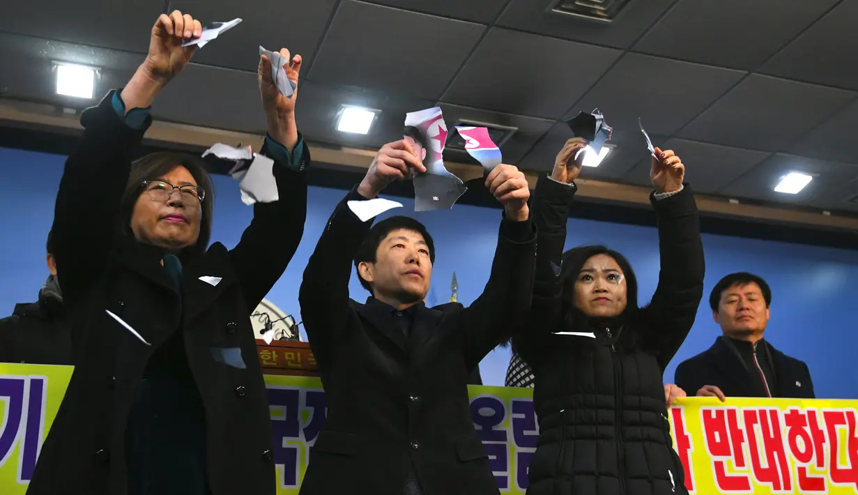 Warga Korea Utara yang membelot menunjukkan foto pemimpin Korea Utara Kim Jong-Un yang dirobek saat konferensi pers di Majelis Nasional di Seoul (24/1). (AFP Photo/Jung Yeon-Je)