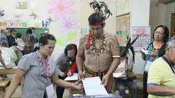 Kepala suku Igorot, Nicolas Cawed dibantu petugas mengambil kertas suara dalam pemilihan presiden di sebuah TPS di Baguio City, Manila Utara, Senin (9/5). Sekitar 50 juta warga Filipina mengikuti pemilihan Presiden. (AFP PHOTO/JJ LANDINGIN)