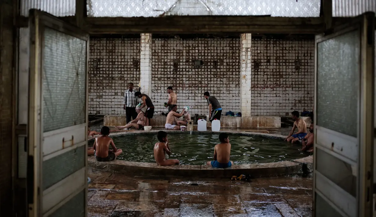 Pengunjung menikmati kolam renang air hangat dari belerang di Hamam Alli, Mosul, Irak, (27/4). Sebelum ISIS mengambil alih Hamam Alil pada 2014, warga Irak selalu mengunjungi spa bersejarah di selatan Mosul ini. (AP Photo/Bram Janssen)