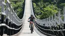 Chrissy Conyers dari Australia melintasi jembatan mengikuti lomba sepeda gunung Himalaya MTB di dekat Mandi, Himachal Pradesh, India utara (4/10). Lomba sepeda ini merupakan perlombaan lintas negara tahunan ke-13. (AFP Photo/Sajjad Hussain)