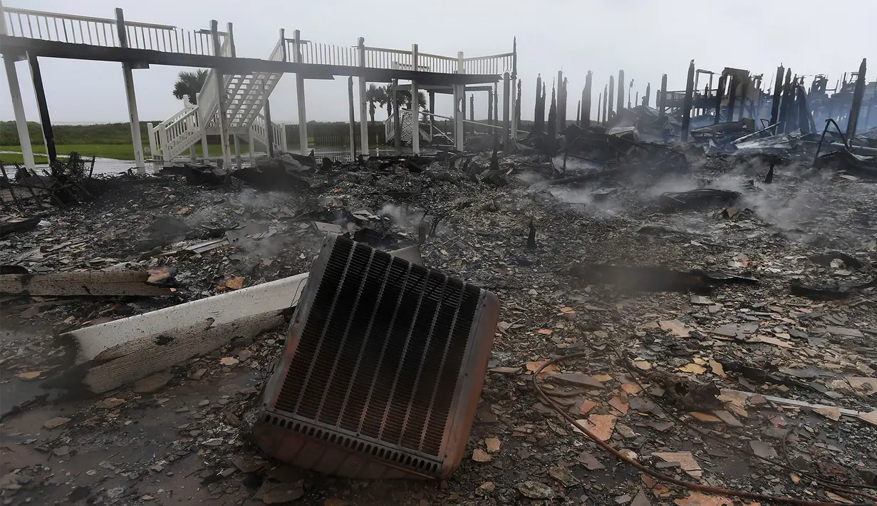 Puing-puing dari tiga kabin di pantai Bolivar yang hangus akibat kebakaran yang terjadi saat dilanda badai Harvey di Texas (26/8). (Guiseppe Barranco/The Beaumont Enterprise via AP)