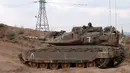 Tentara Israel mengendarai tank tempur Merkava di perbatasan dengan Jalur Gaza, Palestina, Jumat (20/7). Israel mengklaim serangannya dilakukan setelah tentaranya tewas dalam bentrok di perbatasan. (JACK GUEZ/AFP)