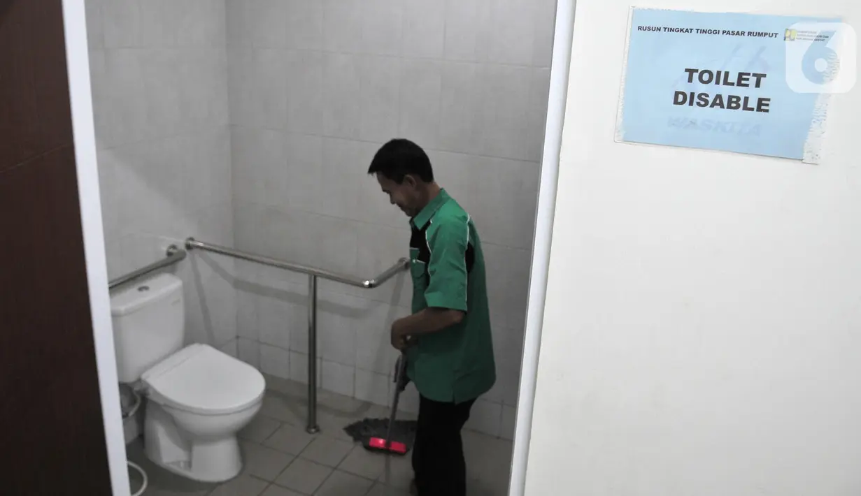 Petugas kebersihan membersihkan toilet disable di pasar Rusunawa Pasar Rumput, Jakarta, Selasa (15/10/2019). Pasar ini telah dilengkapi dengan toilet khusus disabilitas. (merdeka.com/Iqbal Nugroho)