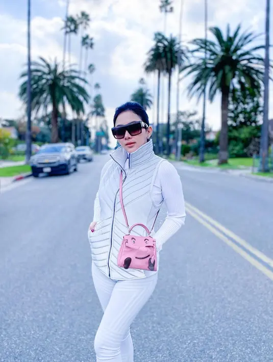 Dengan look yang lebih sporty, Syahrini tidak pernah meninggalkan koleksi tes Hermes-nya. Dengan set olahraga dan vest putih, Syahrini nampak santai menikmati udara Tokyo. Di momen tersebut, Syahrini mengenakan Quelle Idole Kelly Doll Bag Pink Swift Palladium Hardware harga Rp1.751.927.000.