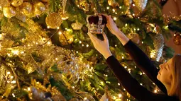 Replika mahkota dipasang pada pohon cemara besar dari Windsor Great Park di ujung aula St. George di Windsor Castle, 30 November 2018. Pohon setinggi 6 meter itu dihias dengan pernak-pernik Natal berwarna emas serta ornamen kerajaan.  (AP/Frank Augstein)